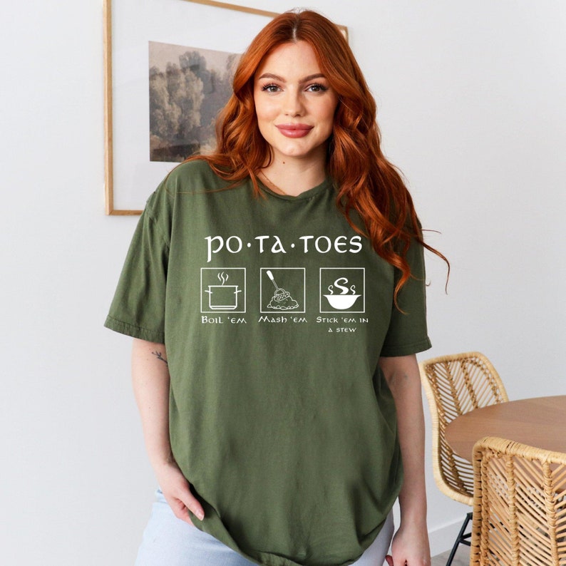 May include: A green t-shirt with a white graphic that says "po-ta-toes" and shows three ways to prepare potatoes: boil, mash, and stick in a stew.