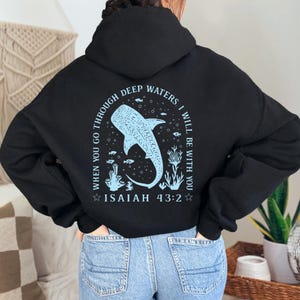 May include: Black hoodie with a light blue graphic on the back. The graphic features a whale shark, coral, and the text "WHEN YOU GO THROUGH DEEP WATERS, I WILL BE WITH YOU. ISAIAH 43:2."
