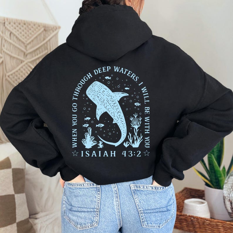 May include: Black hoodie with a light blue graphic on the back. The graphic features a whale shark, coral, and the text "WHEN YOU GO THROUGH DEEP WATERS, I WILL BE WITH YOU. ISAIAH 43:2."