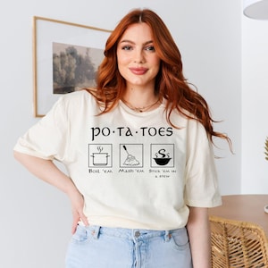 May include: A white t-shirt with a black graphic that says "po.ta.toes" and shows three ways to prepare potatoes: boil, mash, and stick in a stew.