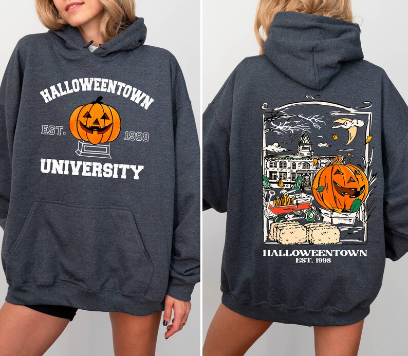 May include: Dark gray hooded sweatshirt with "Halloweentown University" and a jack-o'-lantern graphic on the front. The back features a detailed Halloween scene with a pumpkin, buildings, and the text "Halloweentown Est. 1998".