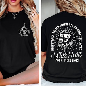 Peut inclure: T-shirt noir avec un graphique blanc d'un cr&acirc;ne qui coule de liquide et le texte "DON'T TALK TO ME WHEN I'M OVERSTIMULATED I WILL HURT YOUR FEELINGS".