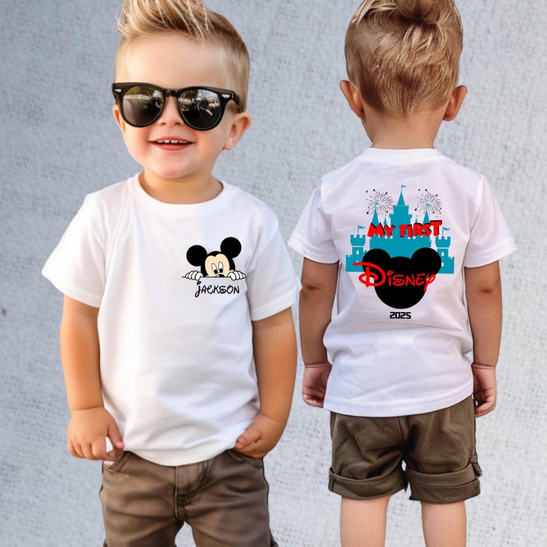 May include: White t-shirts with a Mickey Mouse design. One shirt has "Jackson" printed below the character. The other shirt has "My First Disney" and "2025" printed on the back, with a Mickey Mouse silhouette and castle graphic.
