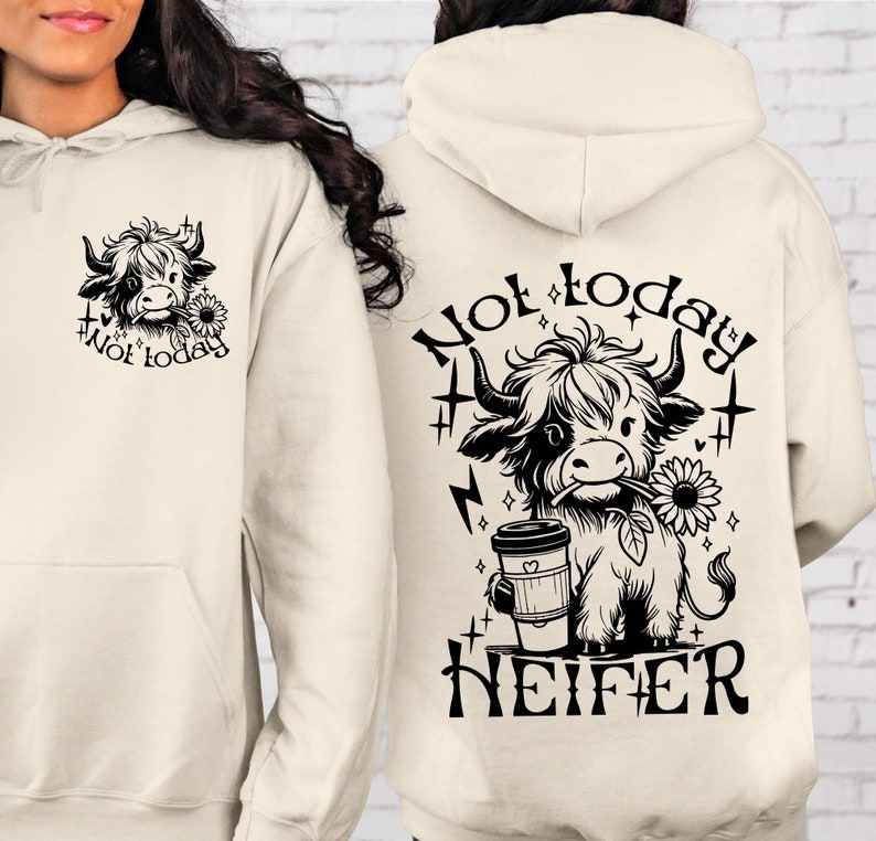 Może przedstawiać: Kremowa bluza z kapturem z czarno-białym rysunkiem krowy trzymającej kubek kawy. Na bluzie nadrukowany jest tekst "Not today" i "HEIFER".