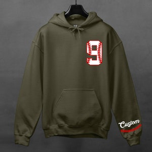 K&ouml;nnte beinhalten: Ein gr&uuml;ner Kapuzenpullover mit einer wei&szlig;en Baseballnummer 9 mit roten N&auml;hten auf der Vorderseite. Das Wort "Custom" steht auf dem &Auml;rmel mit roten N&auml;hten.