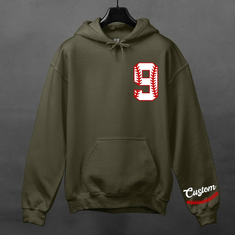 K&ouml;nnte beinhalten: Ein gr&uuml;ner Kapuzenpullover mit einer wei&szlig;en Baseballnummer 9 mit roten N&auml;hten auf der Vorderseite. Das Wort "Custom" steht auf dem &Auml;rmel mit roten N&auml;hten.