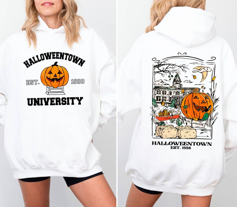 May include: White hooded sweatshirt with a Halloween theme. The front features a pumpkin graphic with the text "Halloweentown University Est. 1998." The back has a detailed illustration of a pumpkin, building, and the text "Halloweentown Est. 1998."