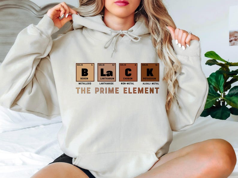 Puede incluir: Una sudadera con capucha blanca con un estampado gr&aacute;fico de las letras "BLaCK" que representan los elementos qu&iacute;micos Boro, Lantano, Carbono y Potasio. El texto "THE PRIME ELEMENT" est&aacute; impreso debajo del gr&aacute;fico.