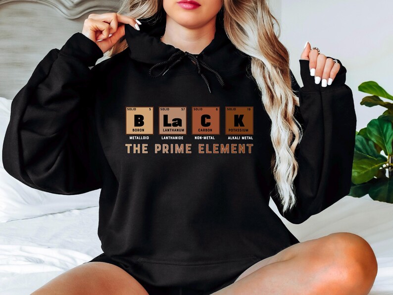 Puede incluir: Sudadera con capucha negra con un estampado gr&aacute;fico de la tabla peri&oacute;dica de los elementos para las letras "B", "La", "C" y "K" que representan la palabra "Black". El texto "The Prime Element" est&aacute; impreso debajo del gr&aacute;fico.