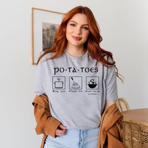 May include: A gray t-shirt with the text "po-ta-TOES" and three icons depicting different ways to prepare potatoes: "BOIL 'EM", "Mash 'em", and "STICK 'EM IN A STEW".