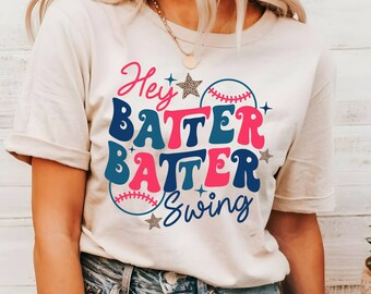 May include: A white t-shirt with a retro-style graphic design that says "Hey Batter Batter Swing" with baseballs and stars.