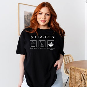 May include: A black t-shirt with a white graphic that says "po-ta-toes" and shows three ways to cook potatoes: boil, mash, and stick in a stew.