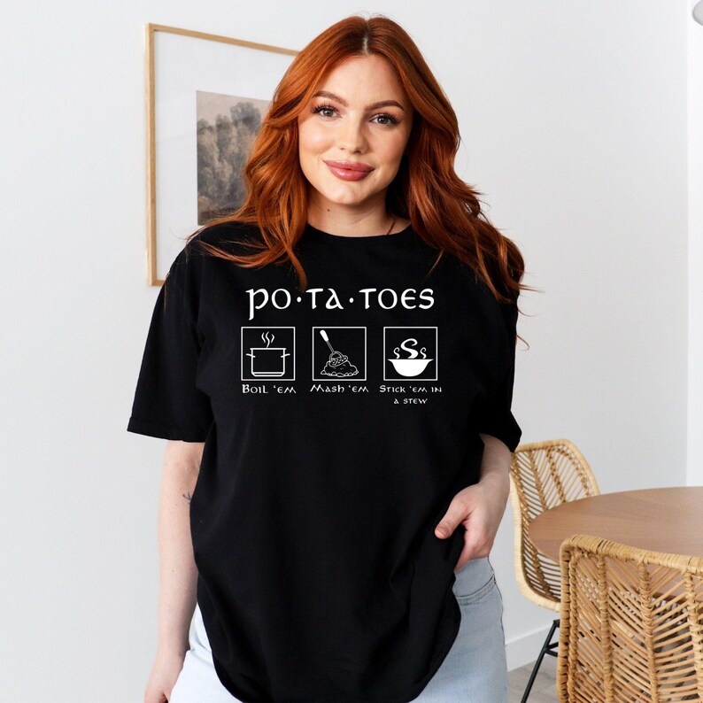 May include: A black t-shirt with a white graphic that says "po-ta-toes" and shows three ways to cook potatoes: boil, mash, and stick in a stew.