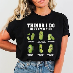 Pu&ograve; includere: Una maglietta nera con una grafica bianca di una serie di sottaceti con facce. Il testo "THINGS I DO IN MY SPARE TIME" &egrave; in cima alla grafica. La grafica mostra sottaceti con il testo "EAT PICKLES", "HUNT FOR THE PERFECT PICKLES", "BUY PICKLES", "TALK ABOUT PICKLES", "THINK ABOUT PICKLES" e "DREAM ABOUT PICKLES".