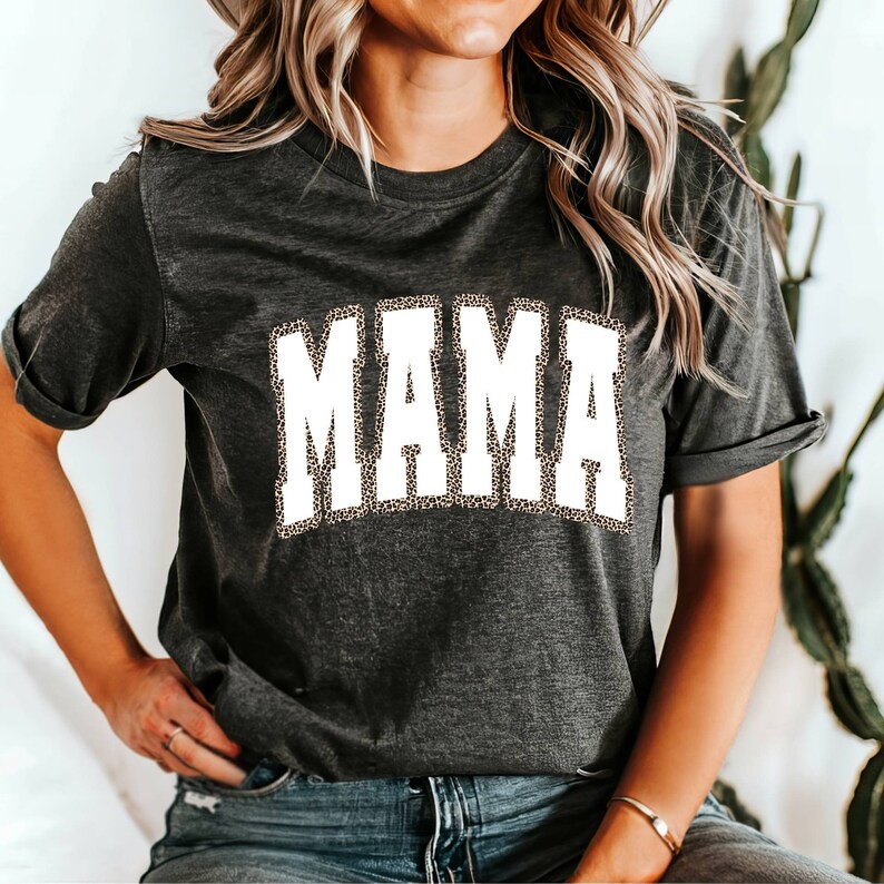 Może przedstawiać: Szary t-shirt z białym nadrukiem "MAMA". Litery są obwiedzione wzorem w panterkę.