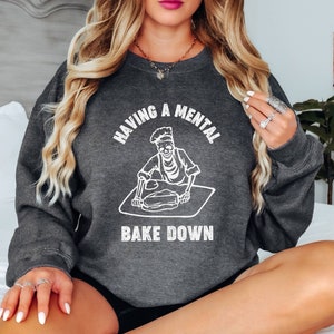 May include: A dark gray sweatshirt with the text "Having a mental bake down" and a skeleton baking.