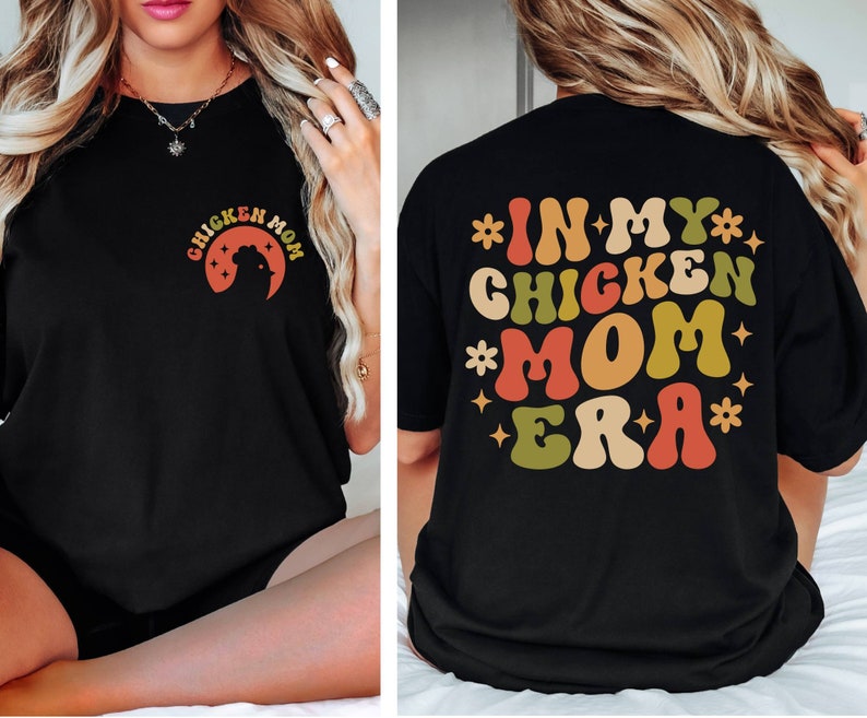 May include: Black t-shirt with a retro-style graphic that says "In My Chicken Mom Era" in colorful letters.