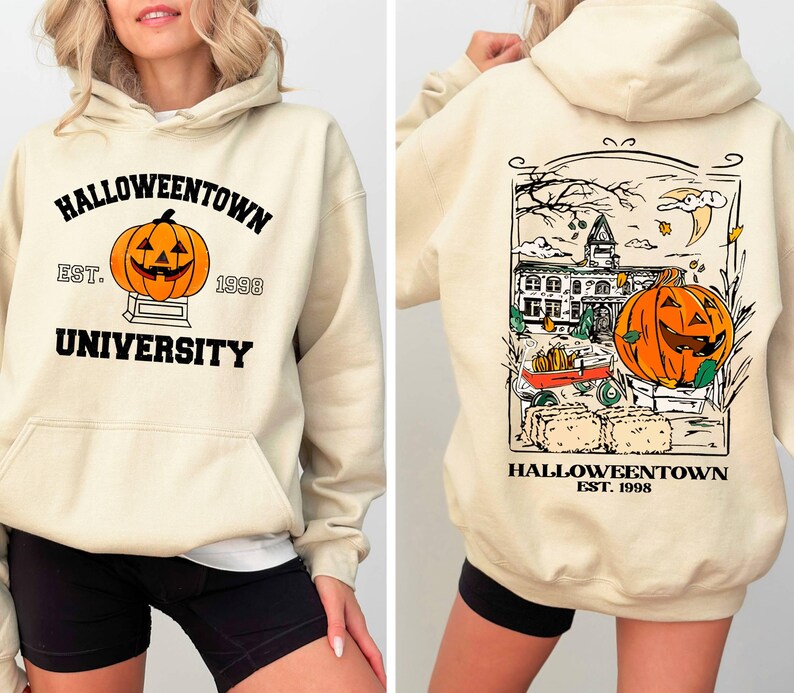 May include: Cream-colored hooded sweatshirt with "Halloweentown University" and a jack-o'-lantern graphic on the front. The back features a detailed illustration of a Halloween scene with a pumpkin and the text "Halloweentown Est. 1998".
