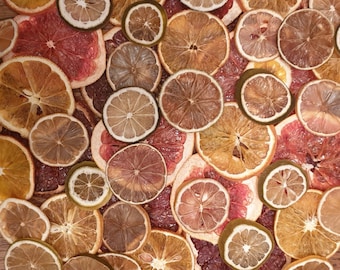 May include: A collection of dried citrus fruit slices, including oranges, lemons, limes, and grapefruits. The slices are arranged in a random pattern and are various shades of yellow, orange, and red.