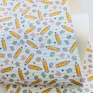 May include: A white background with a repeating pattern of yellow pencils, blue lines, pink flowers, and light blue stars. The pencils are drawn in a cartoon style.