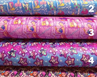 May include: Five rolls of patterned fabric. The top roll is light pink with a repeating design of a woman, musical notes, and flowers. The second roll is blue with comic-style panels. The third roll is pink with a repeating design. The fourth roll is purple with stars. The fifth roll is pink with faces.