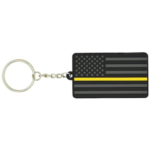 May include: Black and gray American flag keychain with a thin yellow stripe across the middle. The keychain has a silver metal ring and chain.