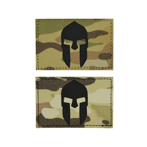 May include: Two black and tan camouflage fabric patches with a black Spartan helmet graphic.
