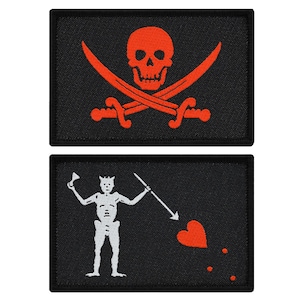 May include: Two black fabric patches with embroidered pirate flags. The top patch features a red skull and crossbones. The bottom patch features a white skeleton holding a spear and a red heart with three red dots.