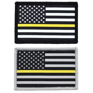 May include: Two rectangular patches featuring the American flag design with a yellow stripe. One patch has a black background with white stripes and stars, while the other has a gray background with black and white stripes and stars. Both have a yellow stripe.