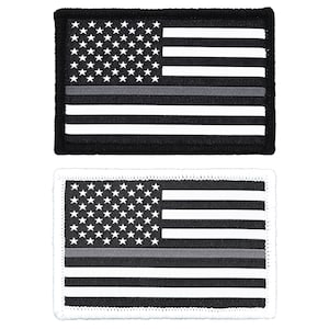 May include: Two embroidered patches featuring the American flag with a thin gray stripe across the middle. The top patch is on a black background and the bottom patch is on a white background.