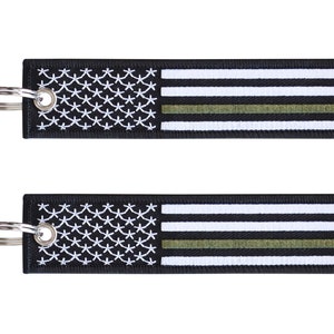 May include: Black and white American flag keychain with a green stripe. The keychain has a silver metal ring.