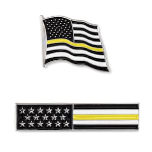 May include: Two thin metal pins with an American flag design. Both flags have a thin yellow stripe across the middle. The top pin is a waving flag and the bottom pin is a rectangular flag.
