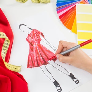 May include: A fashion designer sketches a red dress on white paper using a red marker. A yellow measuring tape, red fabric, and a color palette are also visible.