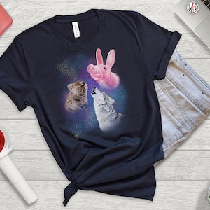 May include: A navy blue t-shirt with a graphic of a pink pig, a wolf, and a bear howling at the moon in a galaxy print.