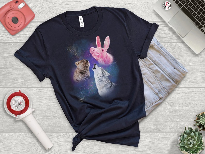 May include: A navy blue t-shirt with a graphic of a pink pig, a wolf, and a bear howling at the moon in a galaxy print.