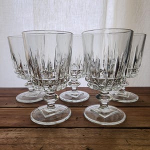 Puede incluir: Juego de seis copas de vidrio transparente con diseño de vidrio cortado. Las copas tienen un tallo alto y delgado y una copa ancha y redonda.