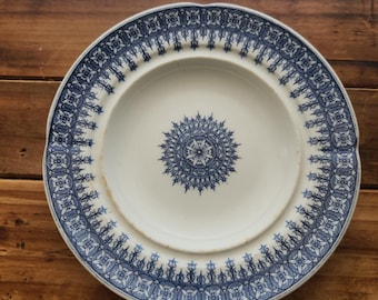 May include: A white ceramic plate with a blue and white floral pattern. The plate has a scalloped edge and a raised center.