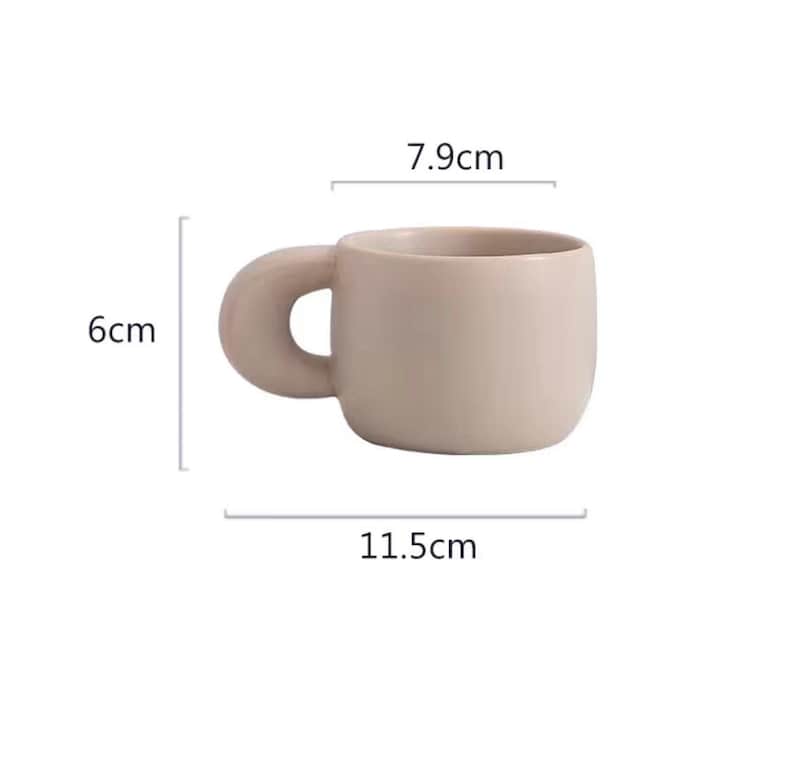Peut inclure: Une tasse en c&eacute;ramique beige avec une anse arrondie unique. La tasse mesure 11,5 cm de large, 6 cm de haut et 7,9 cm de diam&egrave;tre. La tasse a un design simple et minimaliste, id&eacute;ale pour le caf&eacute; ou le th&eacute;.