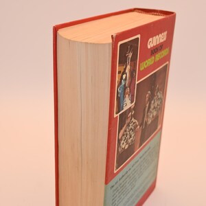 May include: A hardcover book with a red cover and the title "Guinness Book of World Records." The book's spine is visible, showing the pages and the red cover. The cover features images and text.