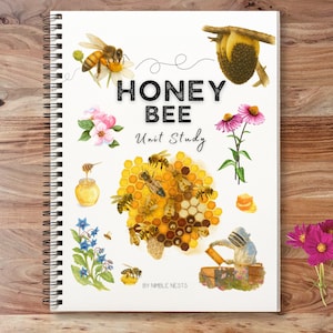 May include: A spiral-bound notebook titled "HONEY BEE Unit Study" with bee-themed illustrations. The cover displays watercolor images of bees, honeycombs, and flowers. The background is a wooden surface.