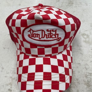 Puede incluir: Gorra de camionero a cuadros rojos y blancos con un parche ovalado rojo que dice "Von Dutch" en letras blancas.