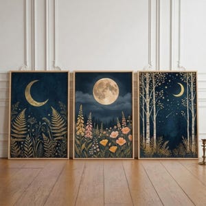 Peut inclure: Un ensemble de trois affiches murales rectangulaires dans des cadres en bois clair. L'affiche de gauche montre un croissant de lune doré au-dessus de fougères. Celle du centre présente une pleine lune sur un champ de fleurs sauvages.