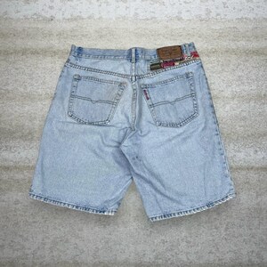 Könnte beinhalten: Hellblaue Jeansshorts mit Gesäßtaschen und einem Lederaufnäher. Die Shorts haben ein klassisches Fünf-Taschen-Design und eine verwaschene Optik. Die Shorts sind ein lässiger Stil.
