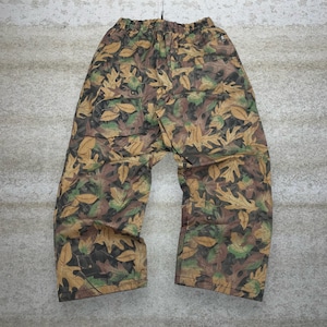 May include: Loose-fitting pants with an all-over leaf pattern in shades of brown, green, and tan. The pants have an elastic waistband and a relaxed fit. The fabric appears to be lightweight and suitable for casual wear.