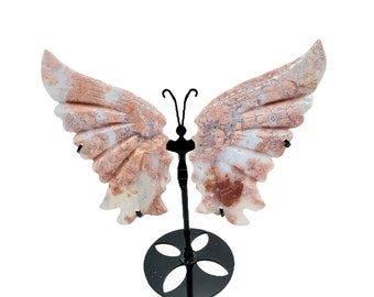 May include: A pink and white marble butterfly sculpture on a black metal stand. The butterfly has intricate details and a delicate design.