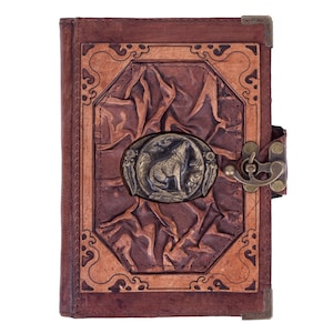 May include: A brown leather-bound journal with a decorative metal clasp and a wolf design on the front cover.