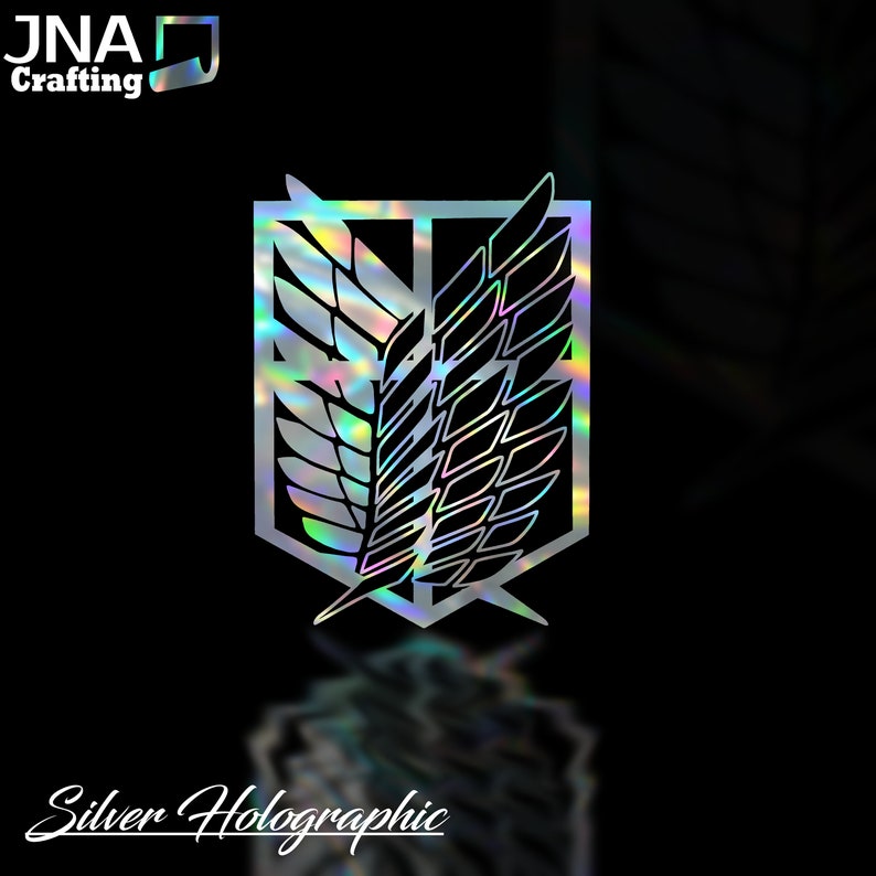 Puede incluir: Un emblema hologr&aacute;fico plateado con un dise&ntilde;o de alas estilizadas dentro de un escudo. La imagen incluye el texto "Silver Holographic" y el logotipo "JNA Crafting". El emblema tiene una calidad reflectante e iridiscente.