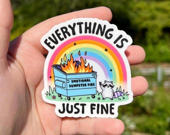 May include: A white sticker with a rainbow, a blue dumpster on fire, and a raccoon with a peace sign. The text on the sticker reads "Everything is just fine" and "Emotional Dumpster Fire".