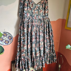 May include: A green floral print dress with a sweetheart neckline and tie straps. The dress has a tiered skirt and a fitted bodice.