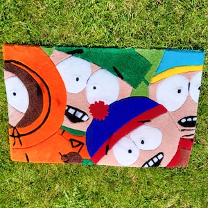 Op de afbeelding: Een kleurrijk viltkleed met de vier hoofdpersonages uit de animatieserie South Park. De personages worden afgebeeld met hun kenmerkende gezichtsuitdrukkingen en kleding. Het kleed is gemaakt van zacht, pluche vilt en is perfect om elke kamer een vleugje whimsy te geven.